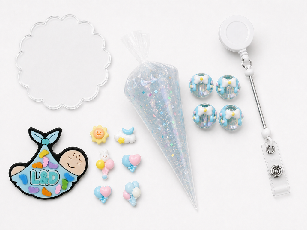 L&D newborn DIY badge reel kit with swaddled baby charm, pastel sky and balloon charms, four blue bow beads, star glitter cream glue and retractable reel