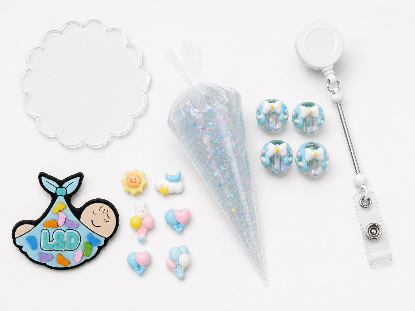 L&D newborn DIY badge reel kit with swaddled baby charm, pastel sky and balloon charms, four blue bow beads, star glitter cream glue and retractable reel
