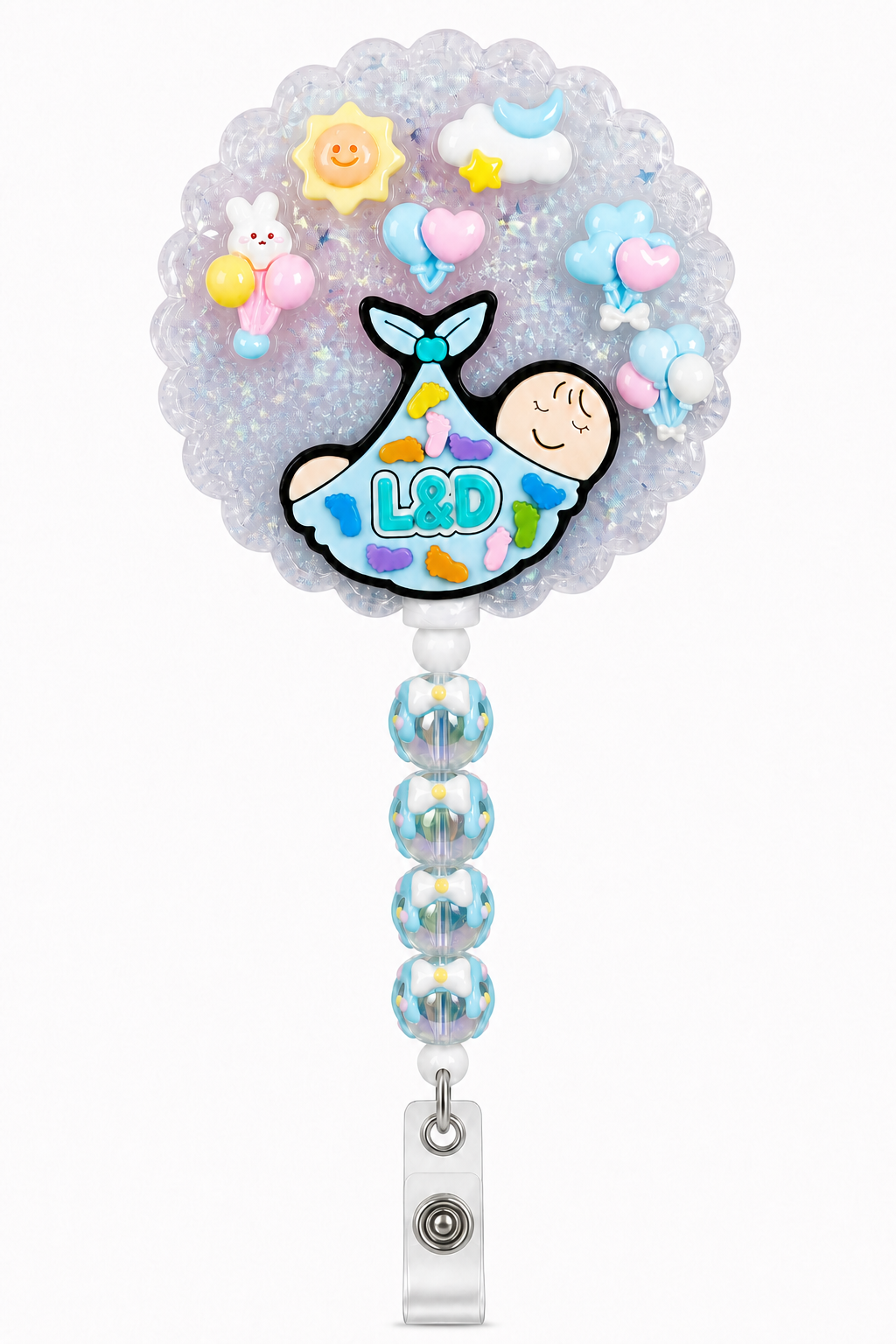 L&D newborn decoden cream badge reel with swaddled baby charm, pastel balloons, sky accents and blue bow beads on a pure white background