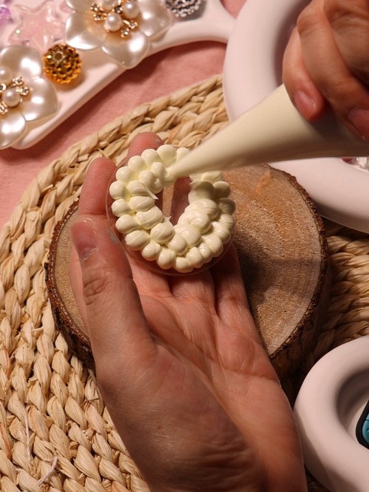 Hands piping cream while making a ReelCute badge reel
